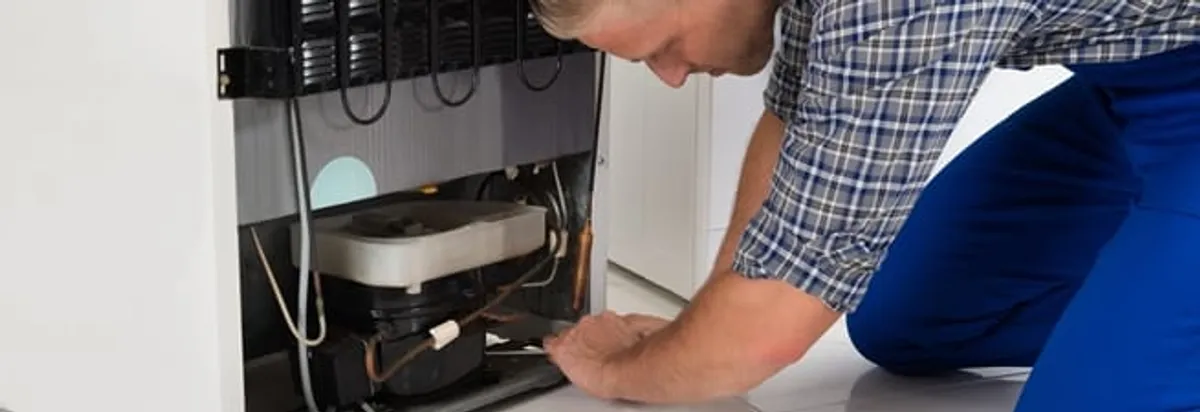 Refrigerator repair technician servicing the compressor and condenser area in Arlington, TX