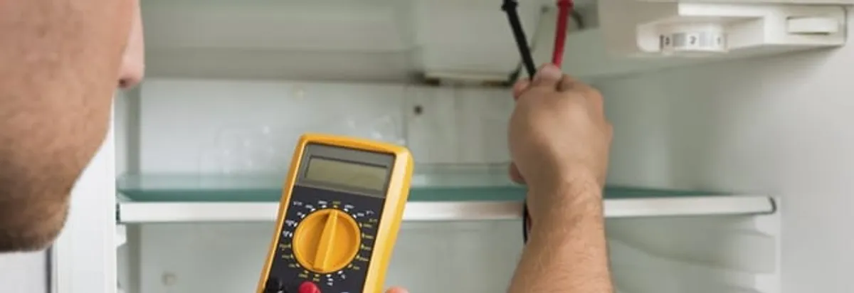Refrigerator repair technician testing electrical components with a multimeter in Arlington, TX