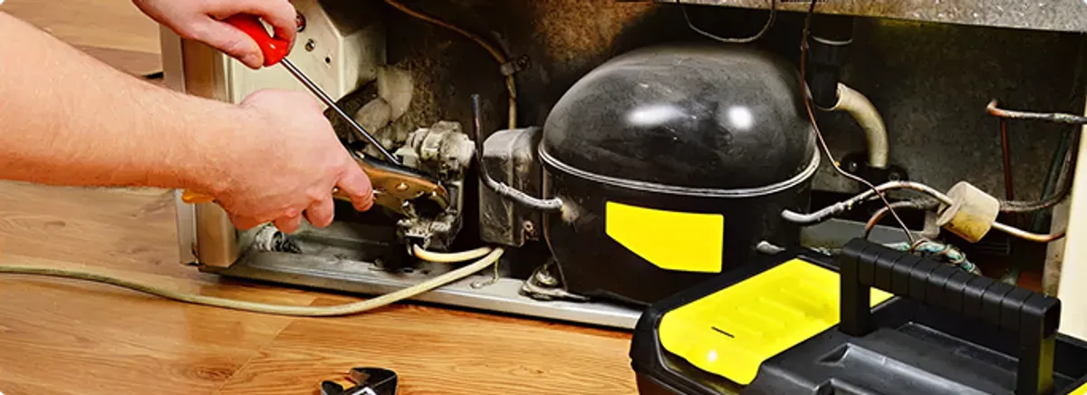 Refrigerator repair technician fixing the compressor and wiring in Arlington, TX